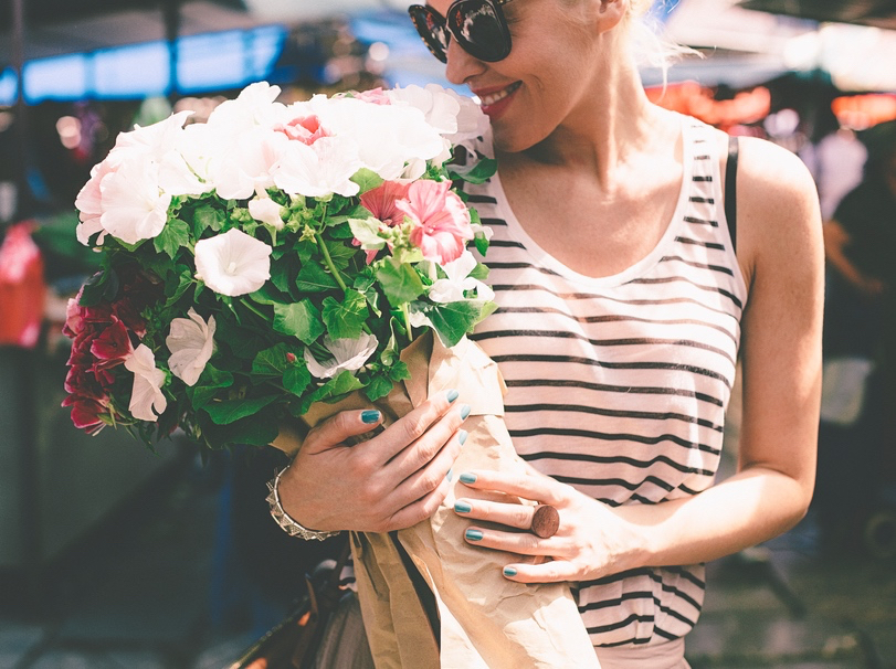 Smiling Caucasian woman smelling the flower bouquet she's just bought.